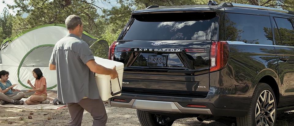 A person using the Ford Split Gate with available Open On Approach to load a cooler in a 2026 Ford Expedition® SUV