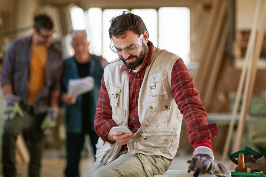 A working man inside a building looking at his smartphone