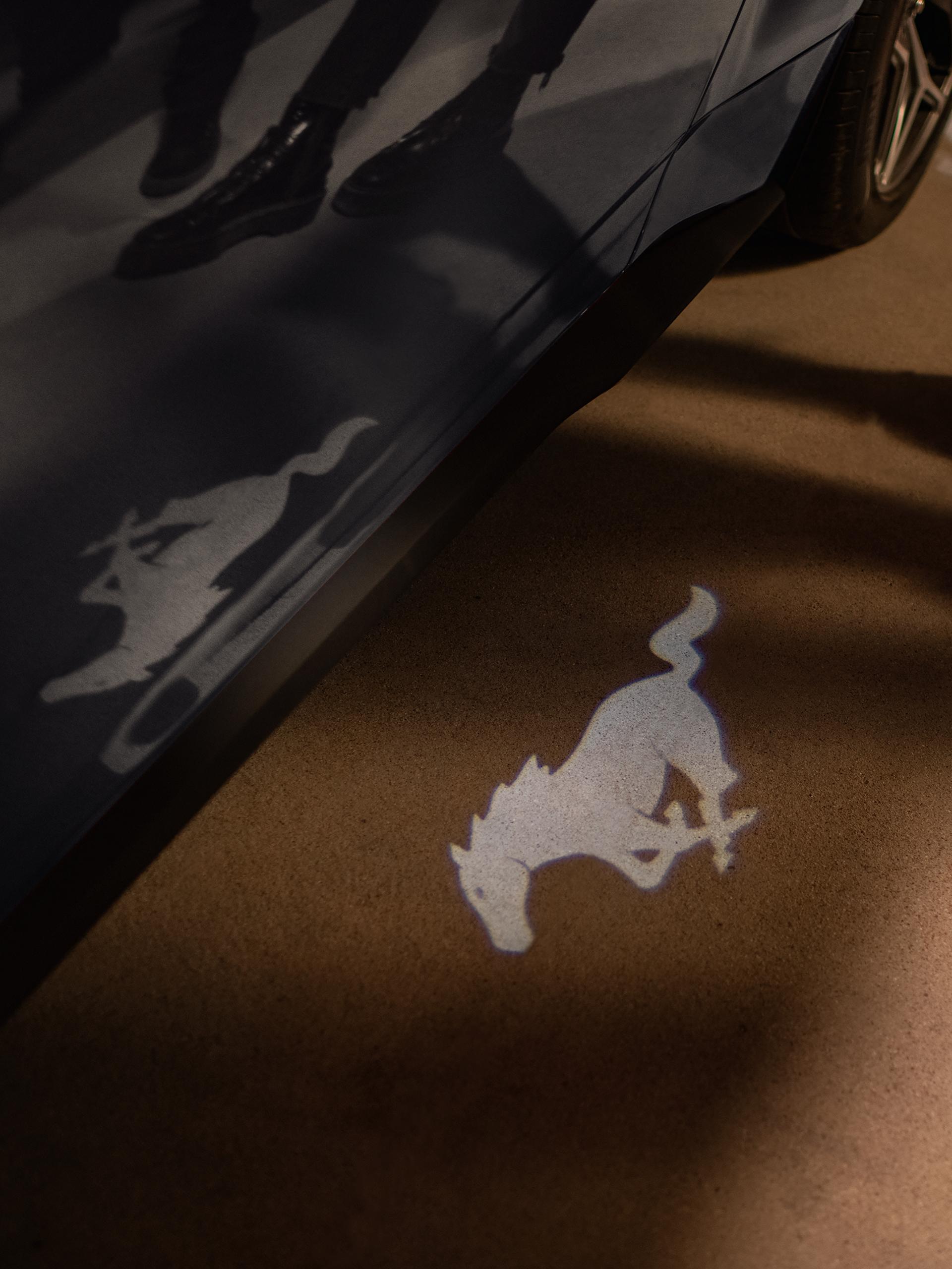 A Ford Mustang® coupe illuminates the ground with its iconic pony logo