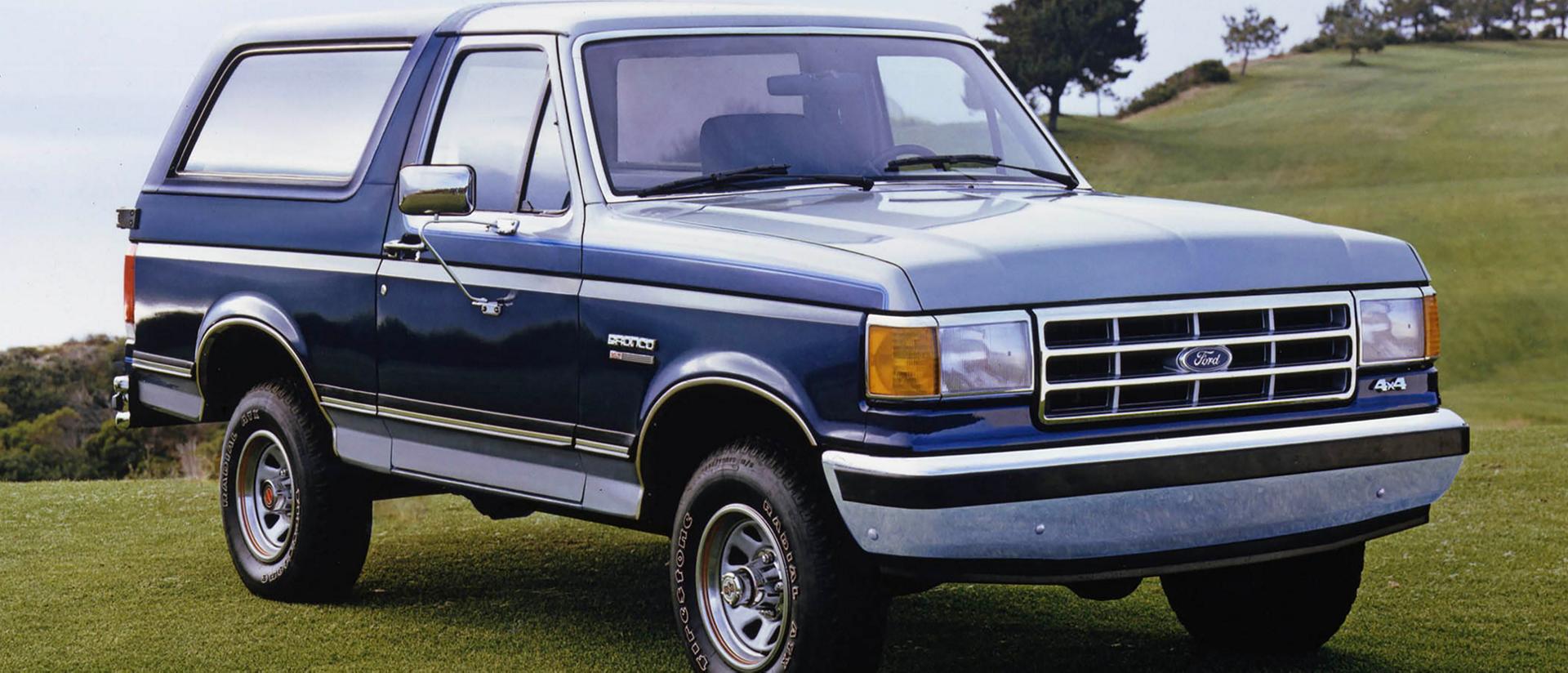 A vintage blue 1987 Ford Bronco® model parked in front of a rocky landscape