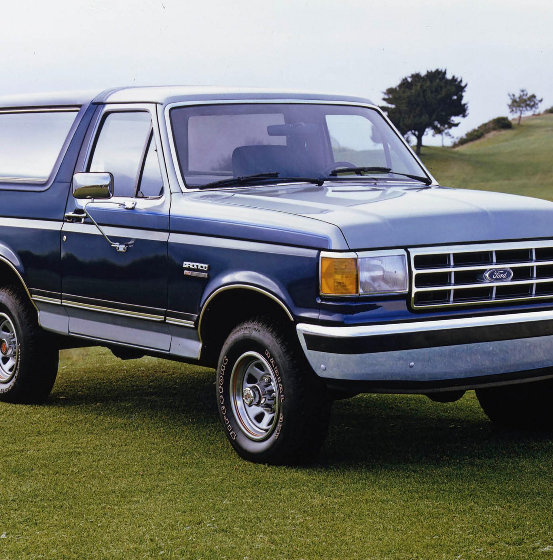 A vintage blue 1987 Ford Bronco® model parked in front of a rocky landscape