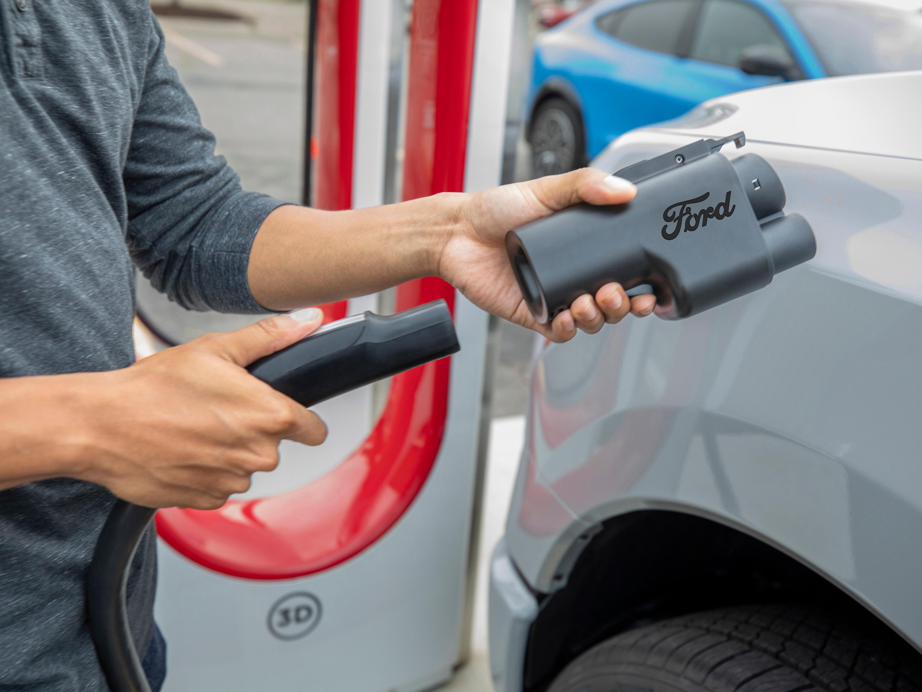 Person holding a NACS adapter for charging their Ford electric vehicle