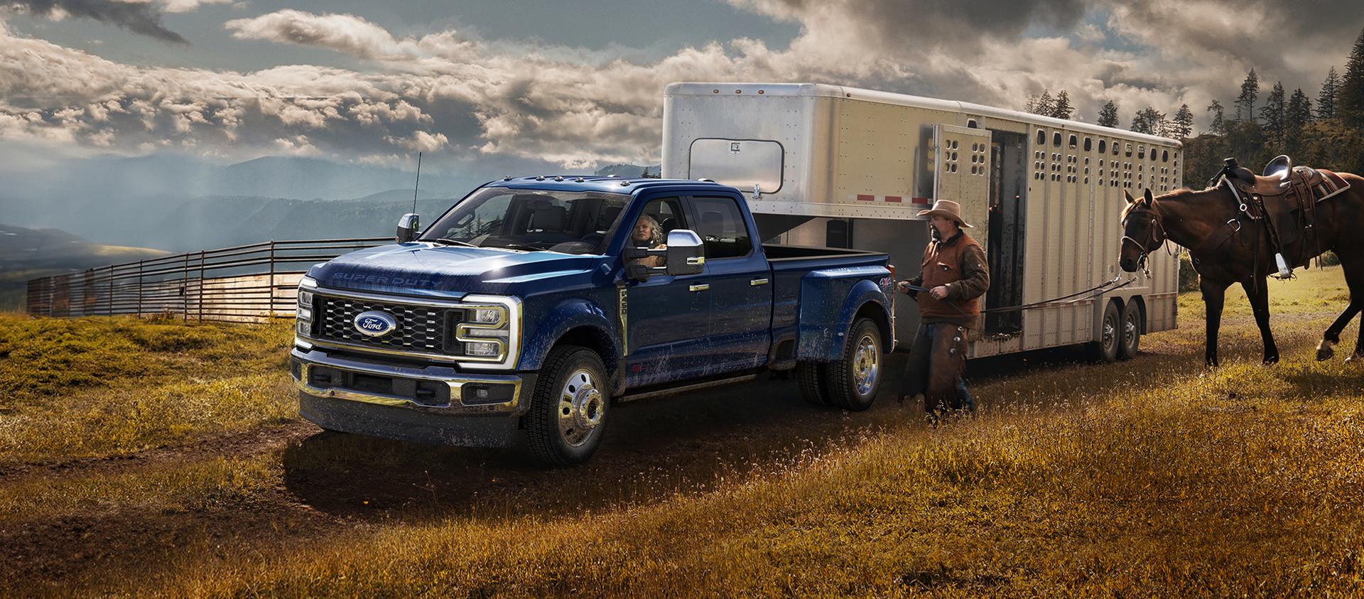 2026 Ford Super Duty® F-450® King Ranch® pickup in Argon Blue towing a horse carrier on a grassy farm