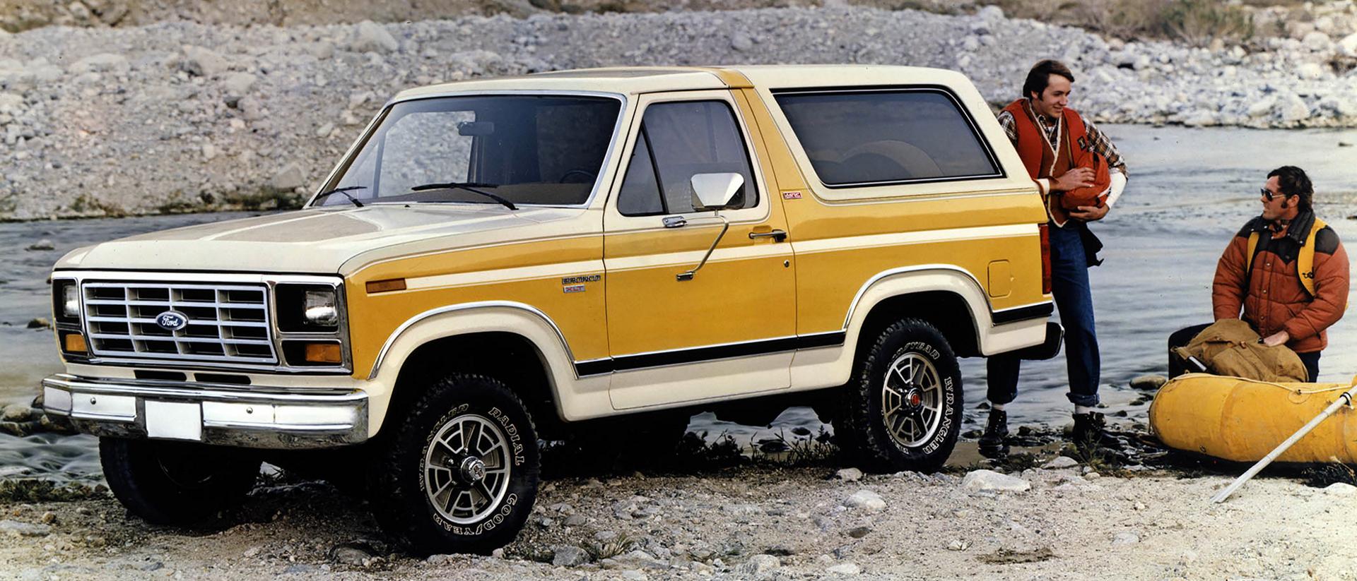 A two-tone yellow 1982 Ford Bronco® model parked along a river bed