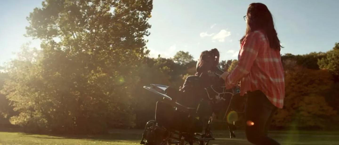 Person in a wheelchair with another person standing behind