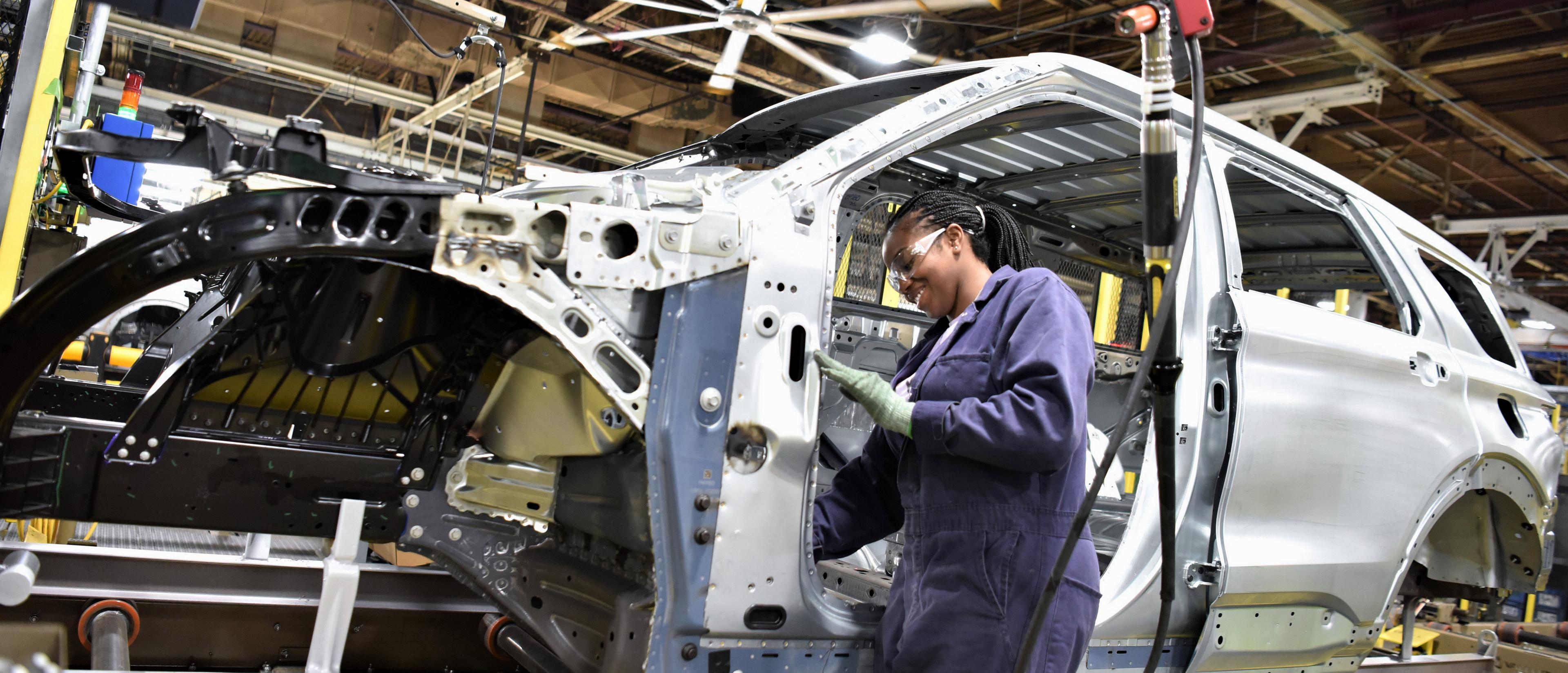 A Ford assembly line worker works on an SUV