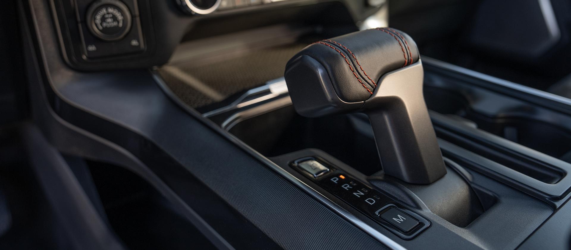A close-up interior view of a center console, focusing on the modern, ergonomic automatic gear shifter