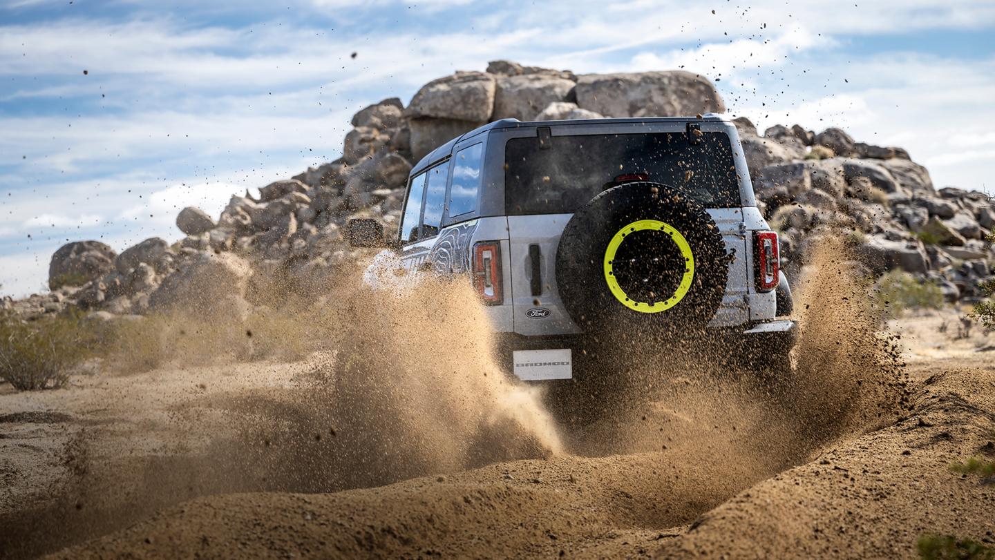A 2027 Ford Bronco® RTR model kicking up dirt near a large rock pile