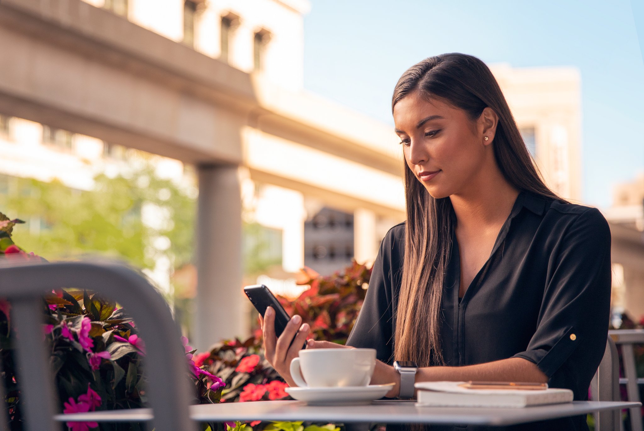 A woman sitting at a table looking at her phone.