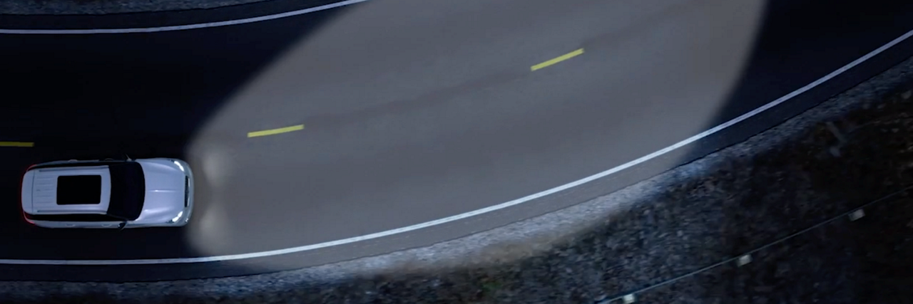 a Lincoln vehicle driving along a curve with headlights at night is shown here