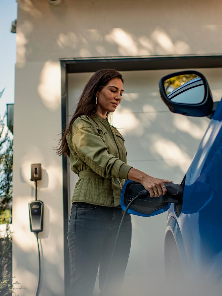 Person plugging a home charger into a 2026 Ford Mustang Mach-E® SUV parked in a driver