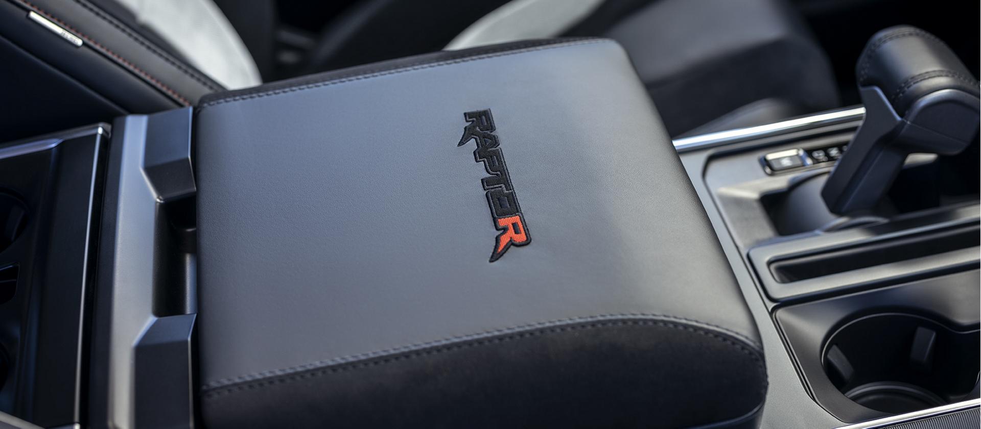 The interior of a 2023 Ford F-150® Raptor® R™, with the distinctive Raptor R logo expertly stitched into its top-of-the-line armrest