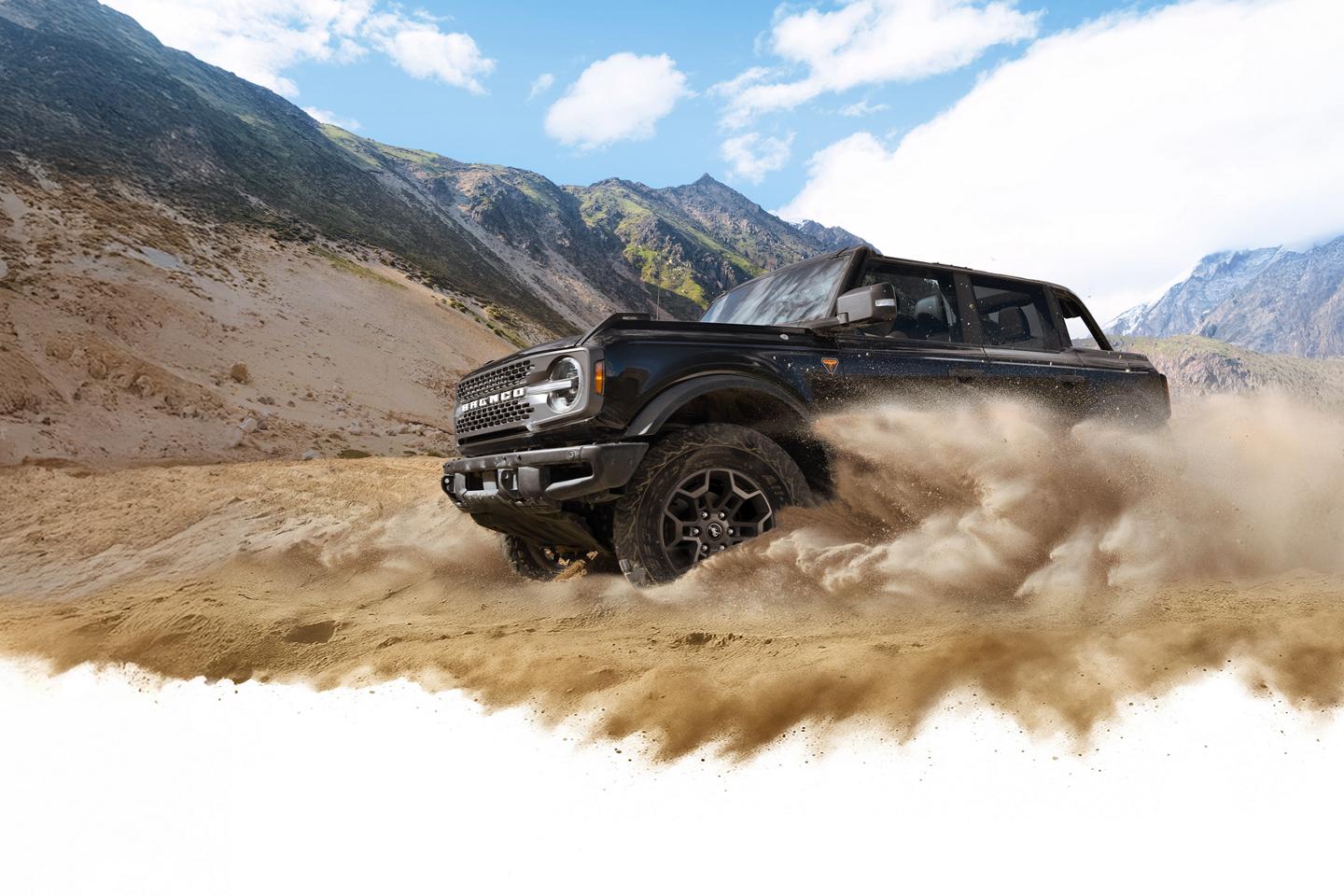 A 2026 Ford Bronco® SUV kicking up dust in a valley beneath rocky hills