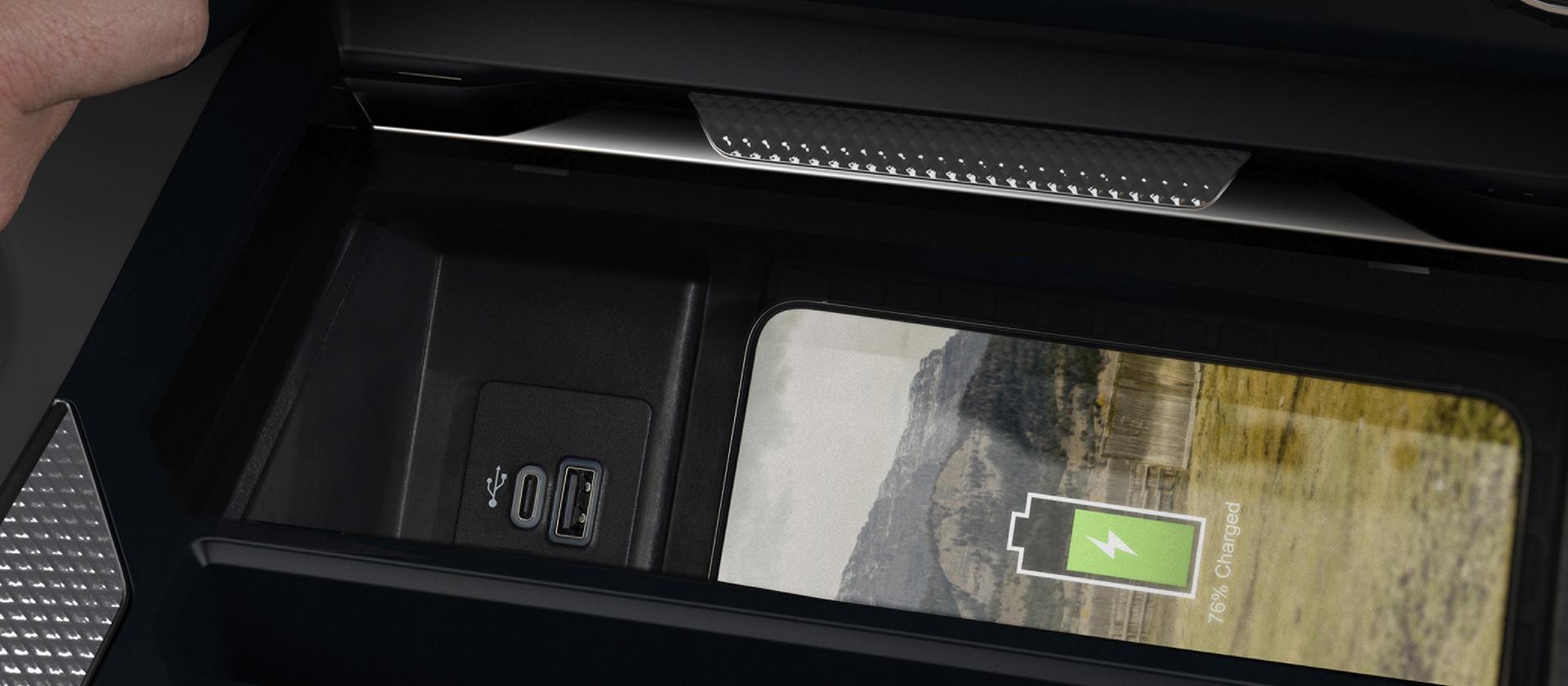 A person's hand adjusting the 2027 Ford Super Duty® pickup Drive Mode knob while a phone charges on the wireless charging pad