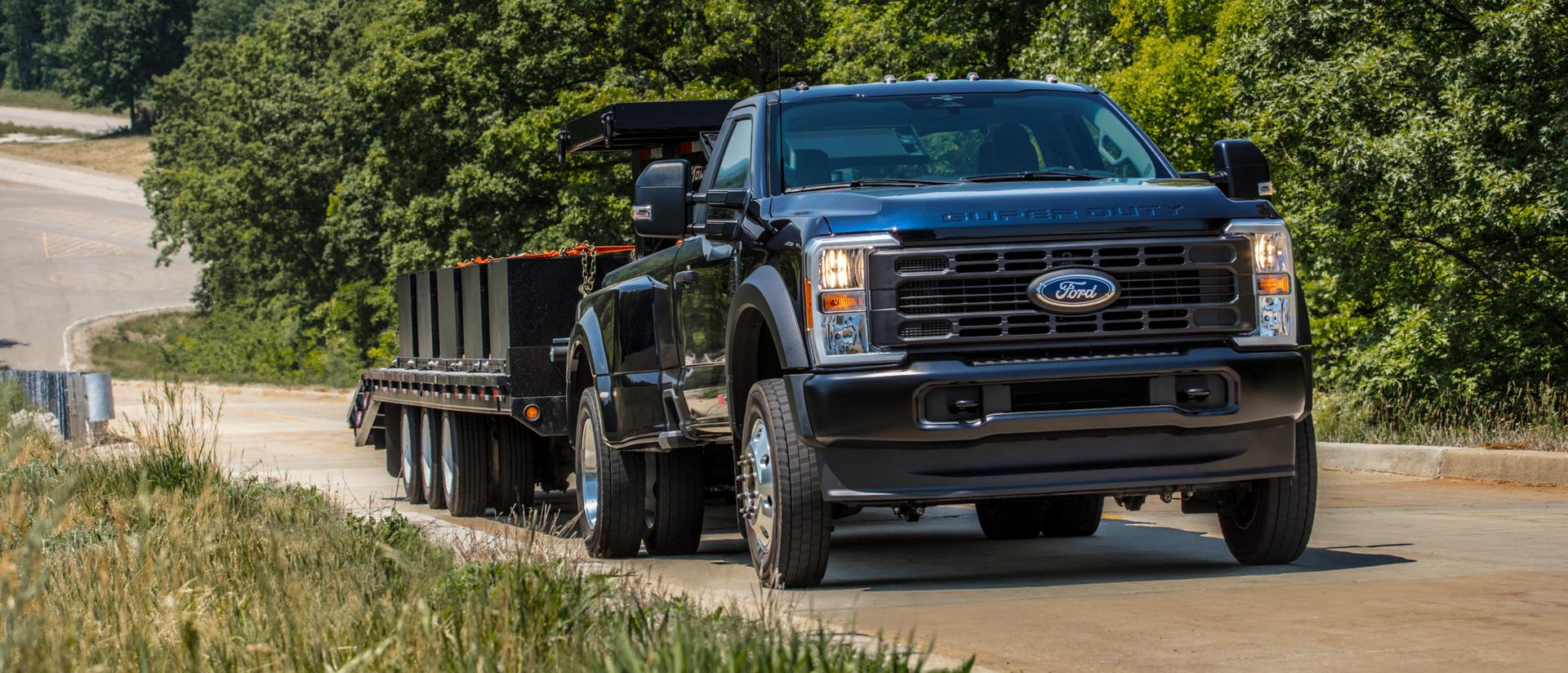 2026 Ford Super Duty® pickup pulling a large flat bed trailer up a paved hill