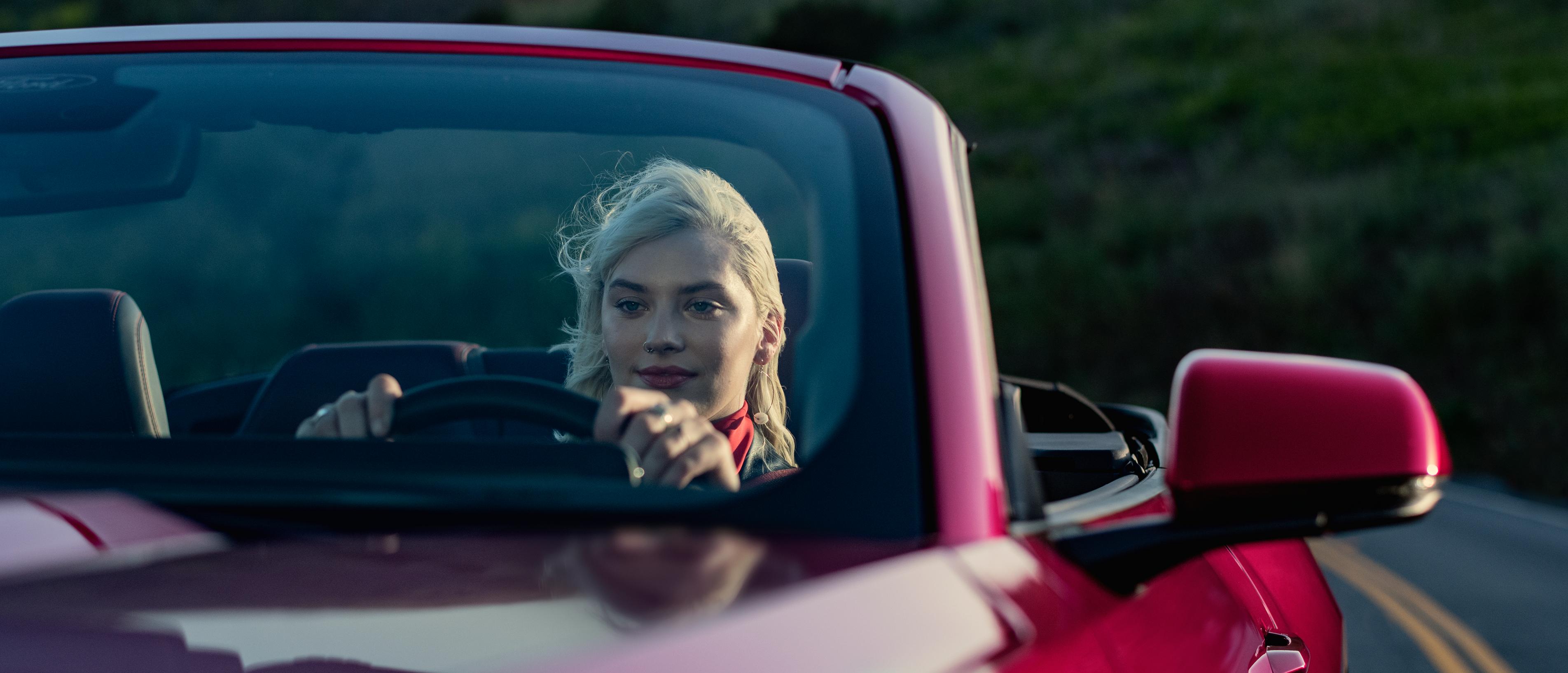 Two Ford Mustangs are lined up with their drivers standing beside them