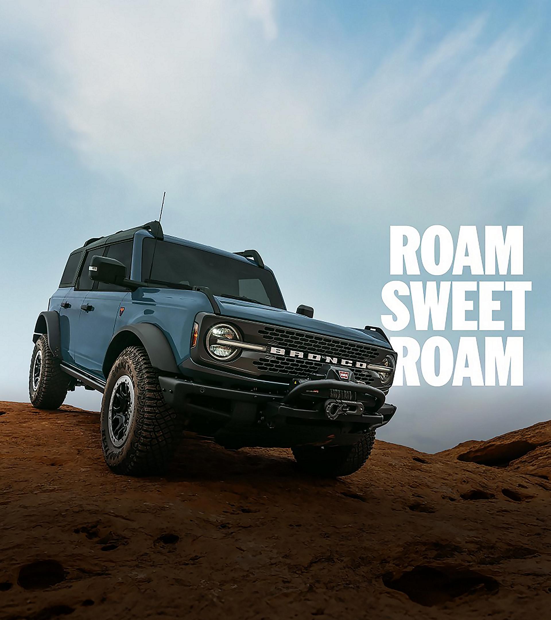 A Ford Bronco® Badlands® SUV parked triumphantly on top of a large rock formation