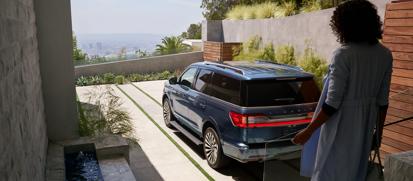 A woman walking towar her Lincoln Navigator.