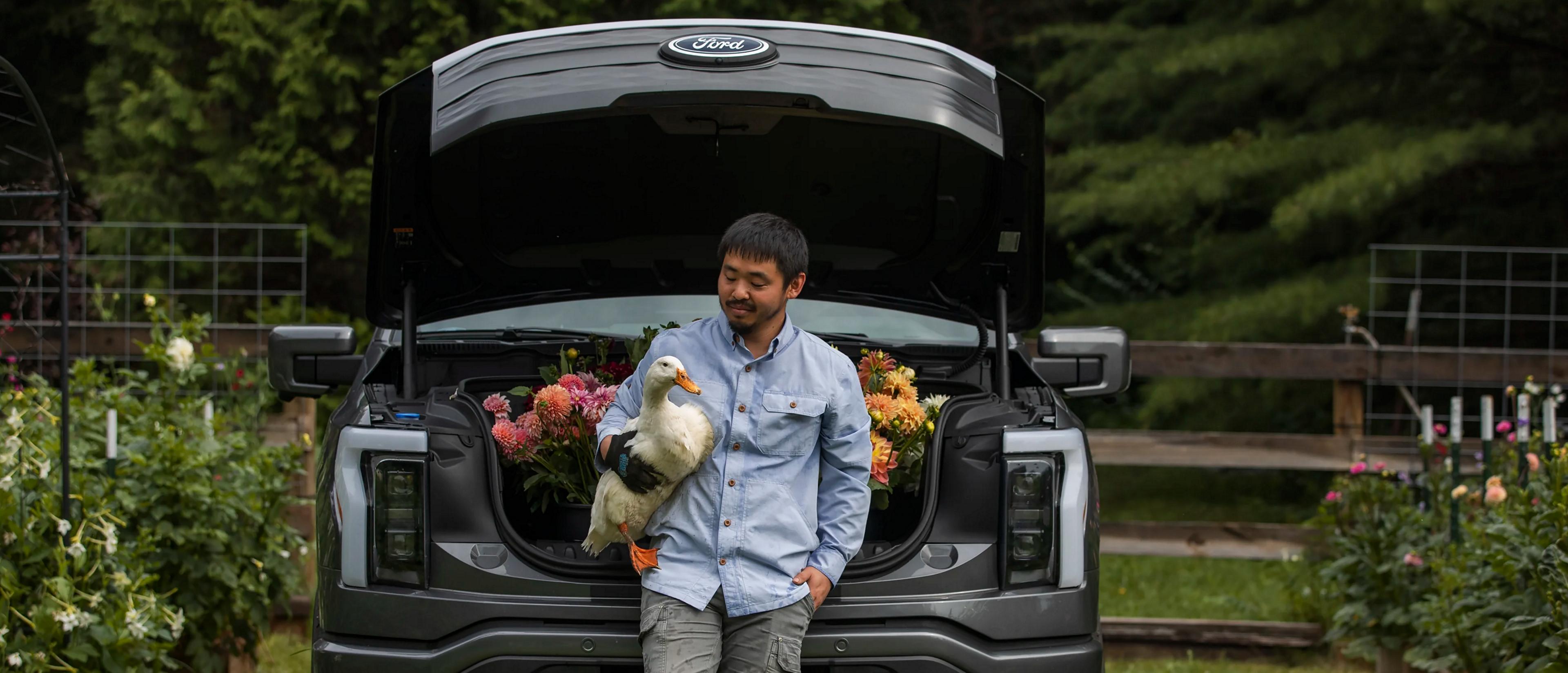 Man standing in front of his Ford F-150 Lightning while holding a duck