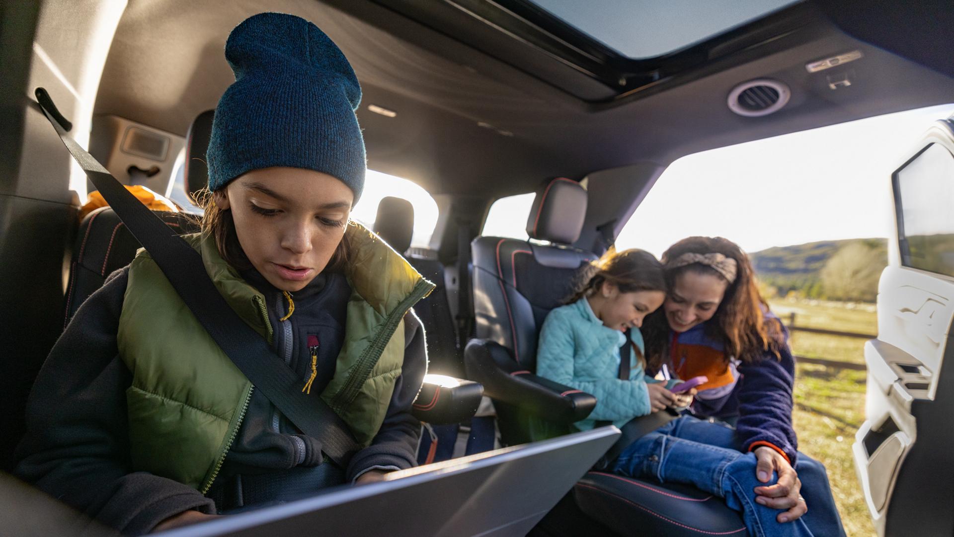 A family using their devices while seated in a parked 2026 Ford Explorer® SUV