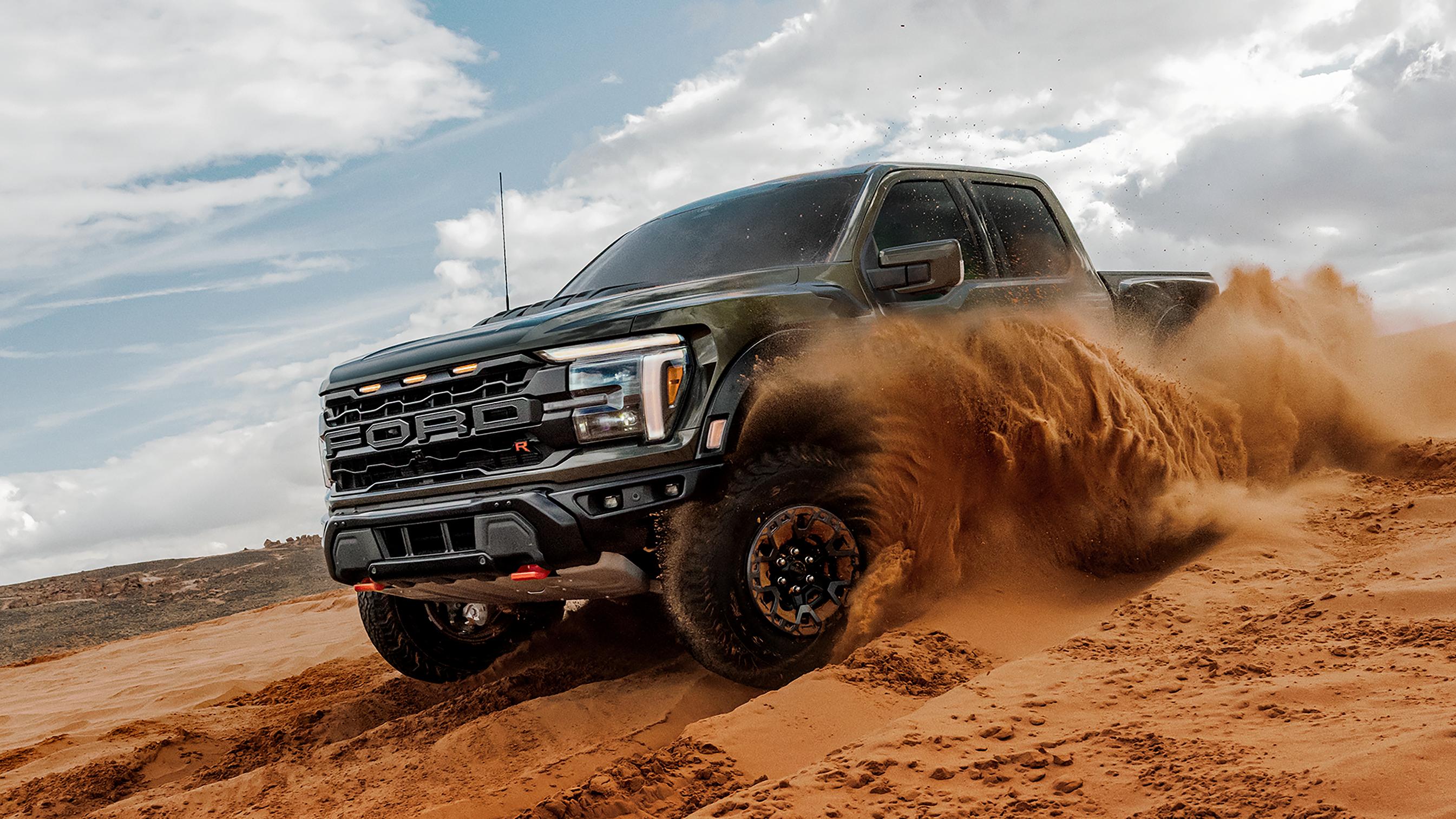 2026 Ford F-150® Raptor R™ truck kicking up sand while being driven in the desert