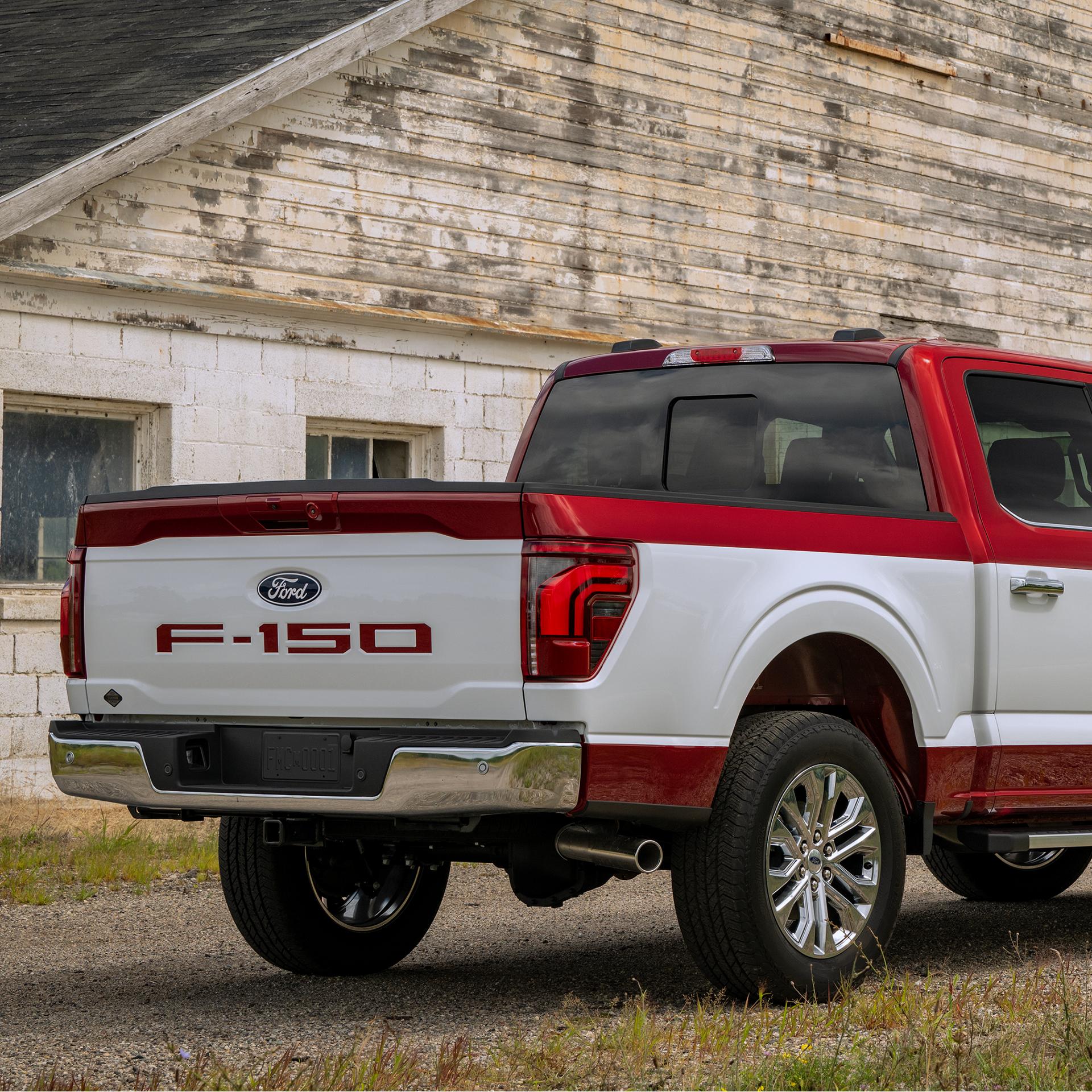 Rear view of a 2027 Ford F-150® Two-Tone Package with a white body, red roof and lower body accents, parked by a building