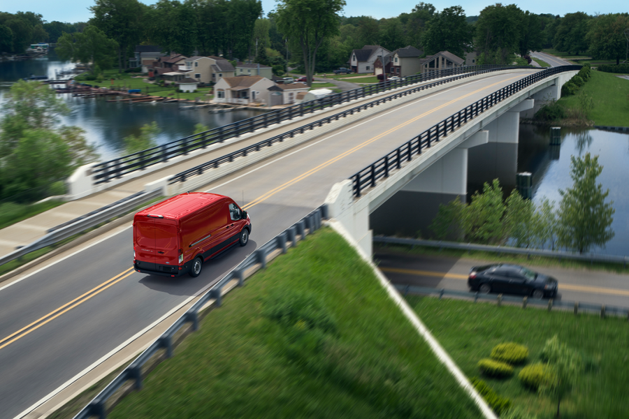 Un Ford E Transit rouge traverse un pont autoroutier