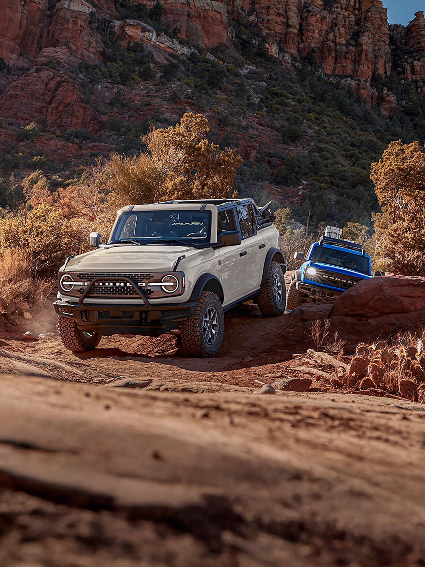 Two 2026 Ford Bronco® SUVs being driven out of a canyon trail