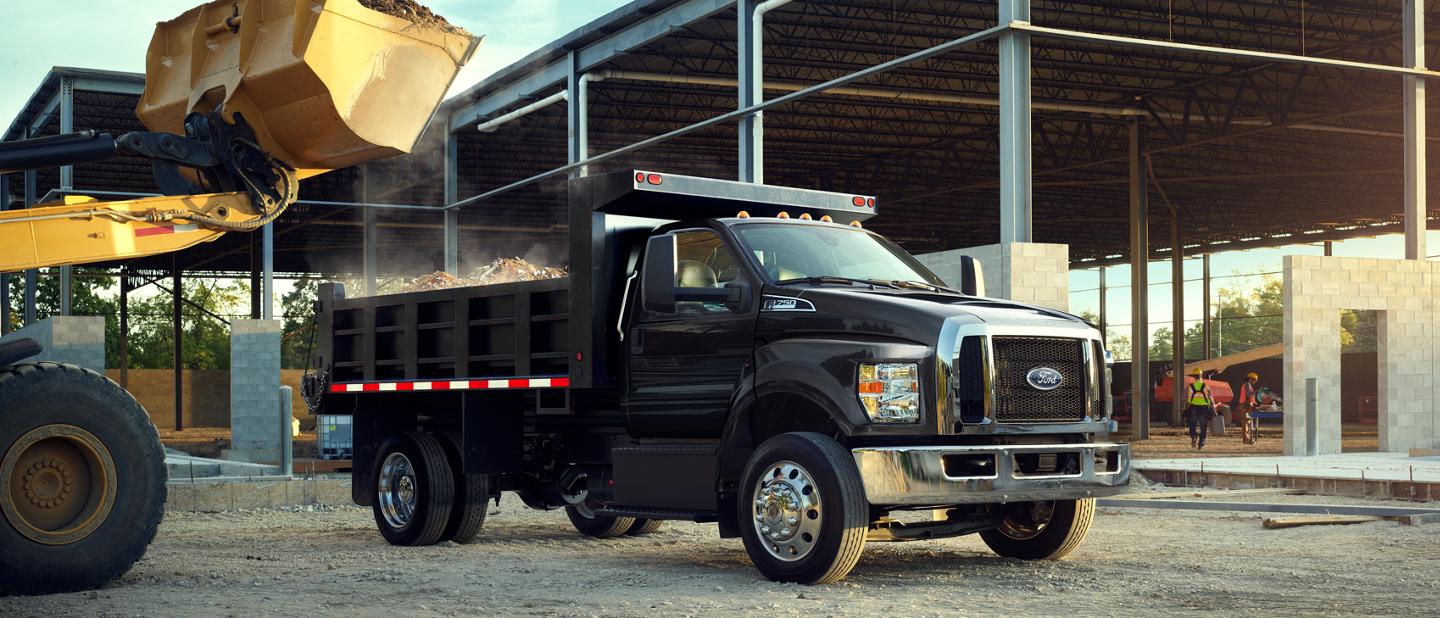 Ford F-750® 2025 à cabine simple en noir agate avec aménagement en camion à benne sur un chantier