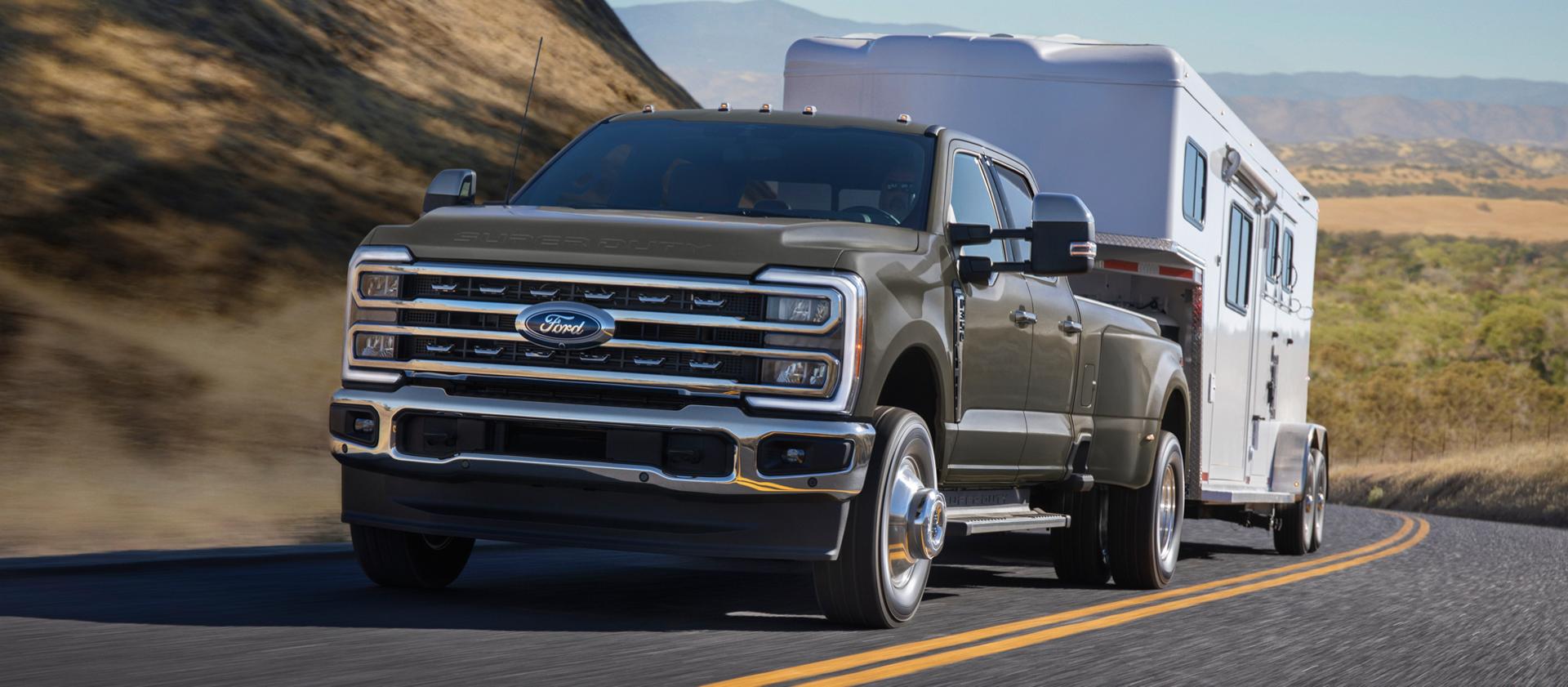 2026 Ford Super Duty® F-350® Lariat® model in Marsh Gray pulling a trailer on a paved road