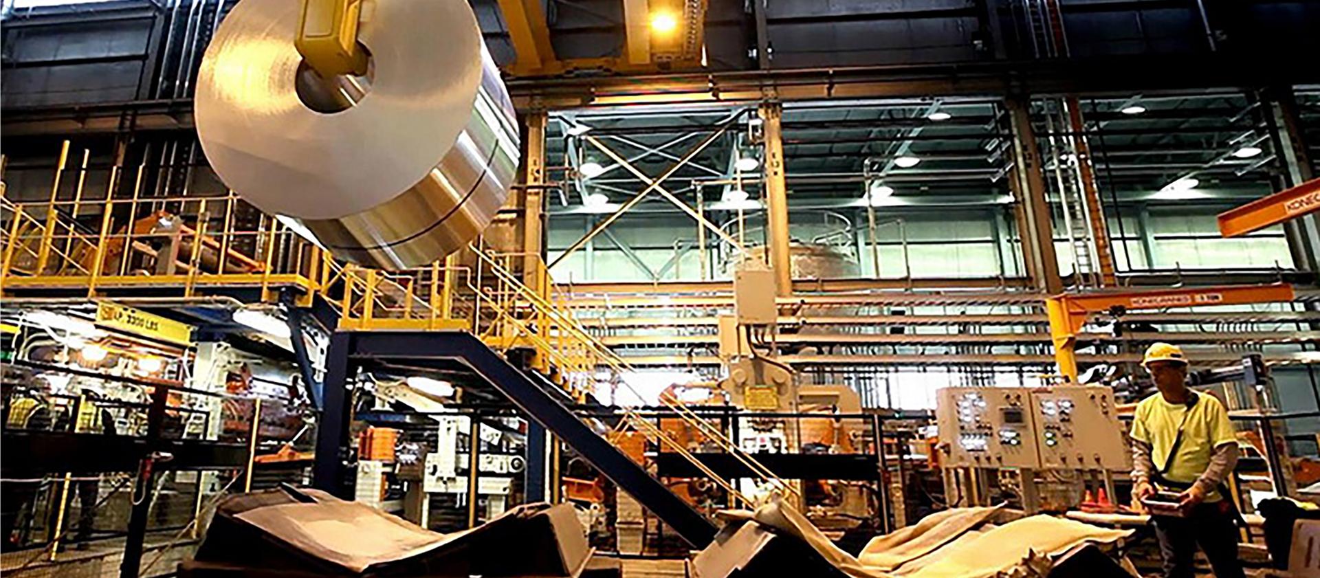 A Ford employee supervises the processing of a steel roll inside the plant