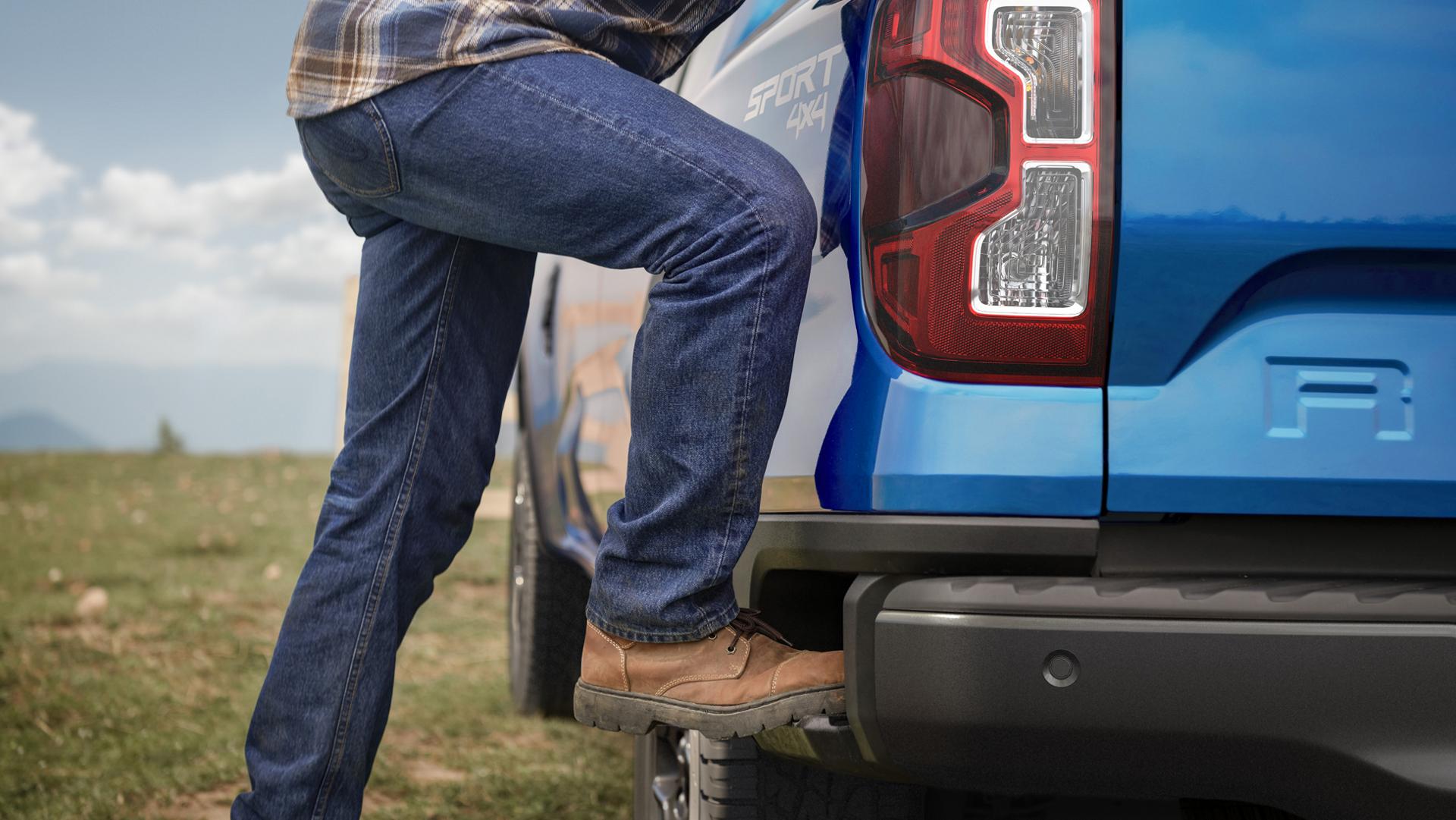Person climbing into the bed of their 2026 Ford Ranger® truck using the integrated box side step