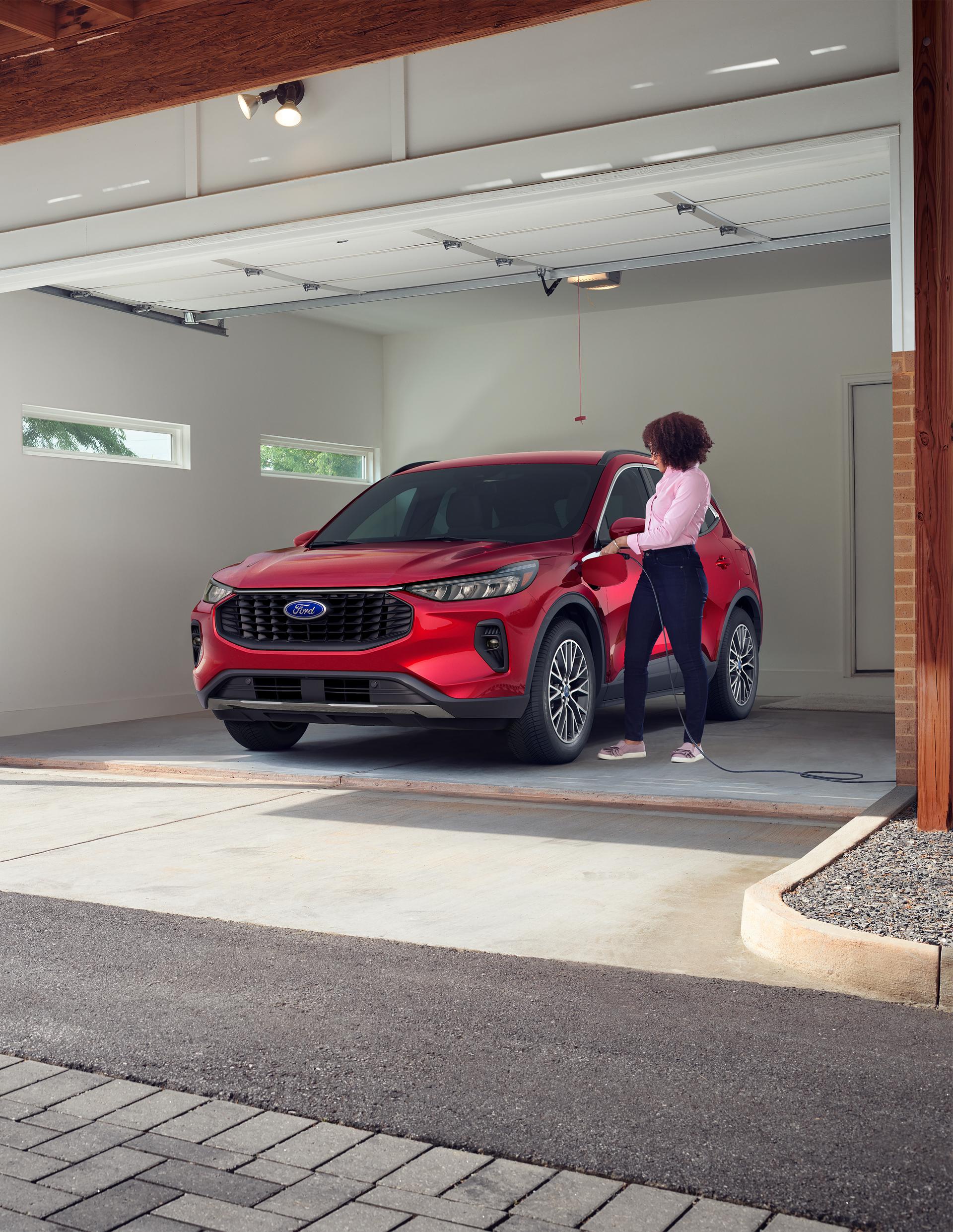 2026 Ford Escape® SUV Plug-In Hybrid model being plugged in by a woman in a garage