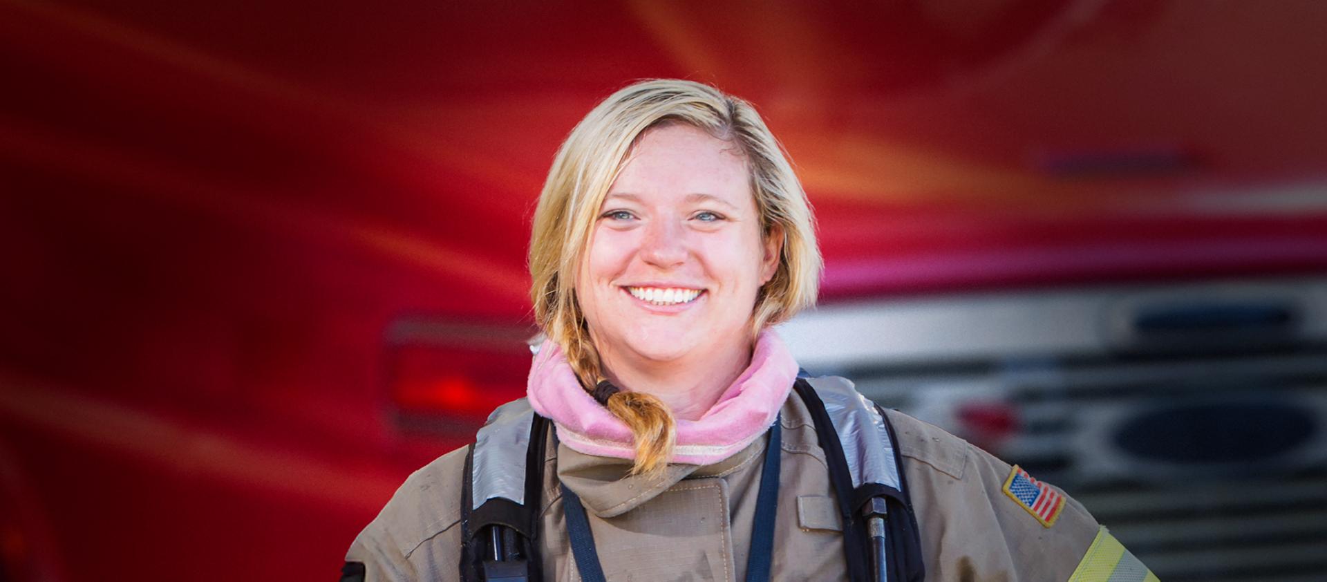 A woman firefighter standing in front of a fire truck
