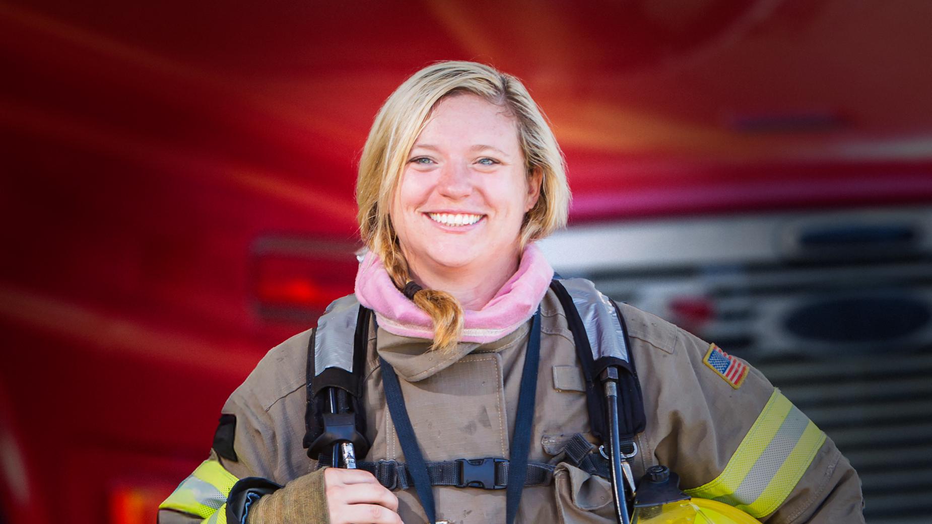 A woman firefighter standing in front of a fire truck