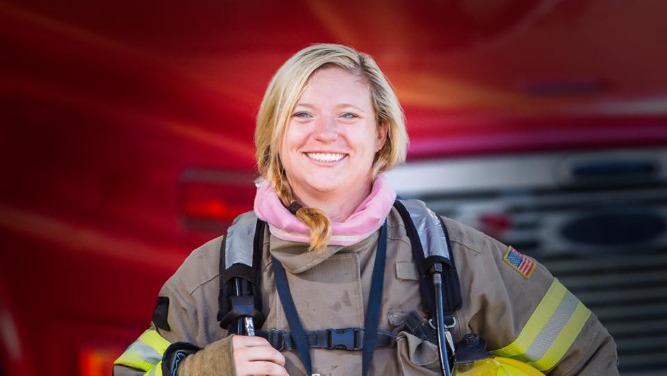 A woman firefighter standing in front of a fire truck