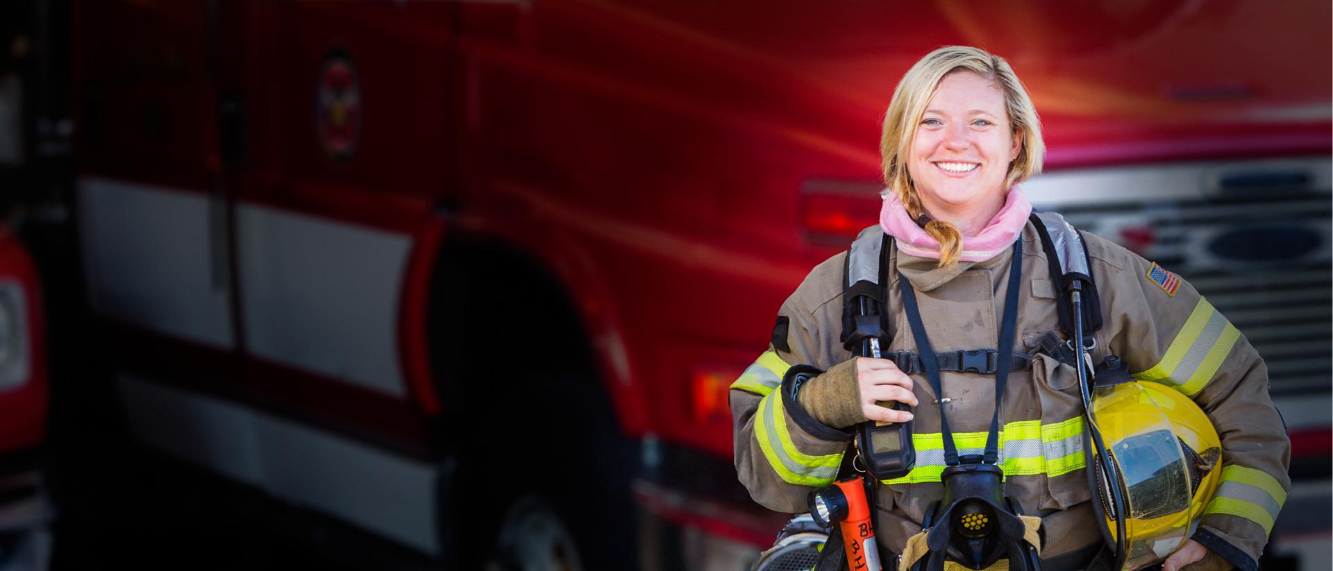 A woman firefighter standing in front of a fire truck