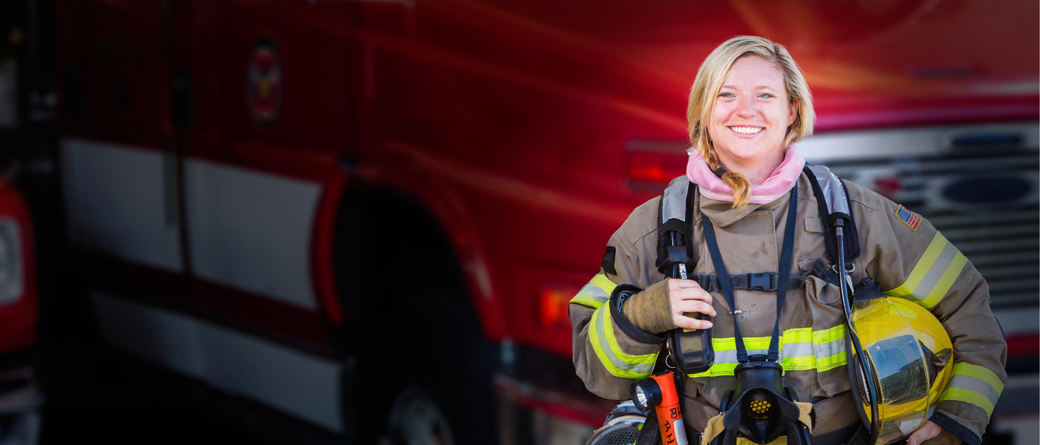 A woman firefighter standing in front of a fire truck