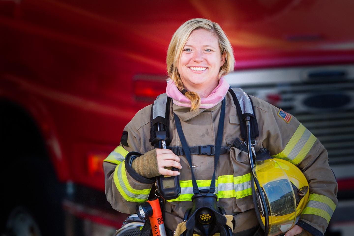 A woman firefighter standing in front of a fire truck