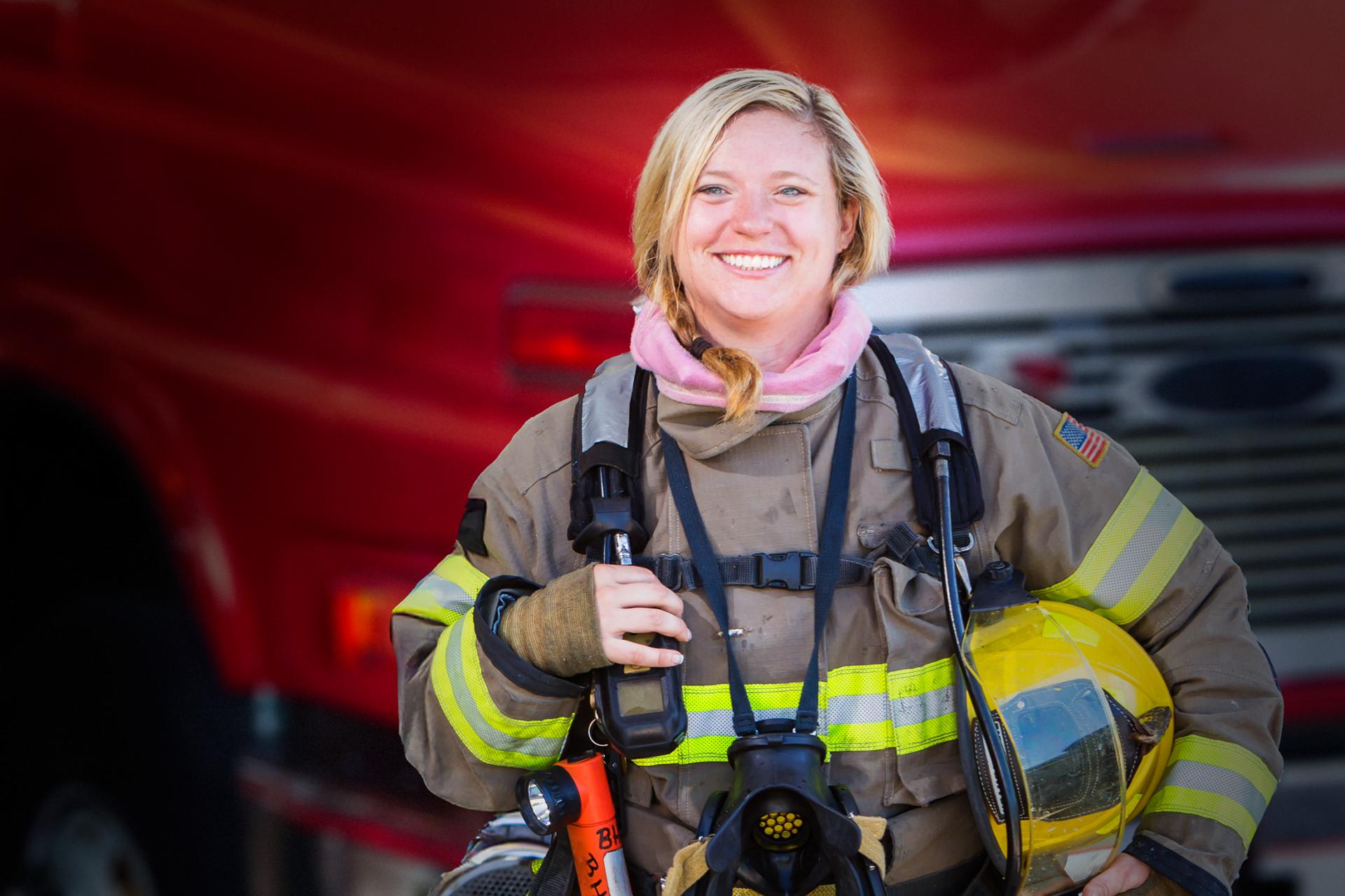 A woman firefighter standing in front of a fire truck