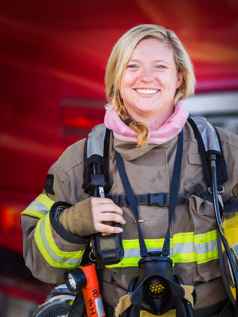 A woman firefighter standing in front of a fire truck
