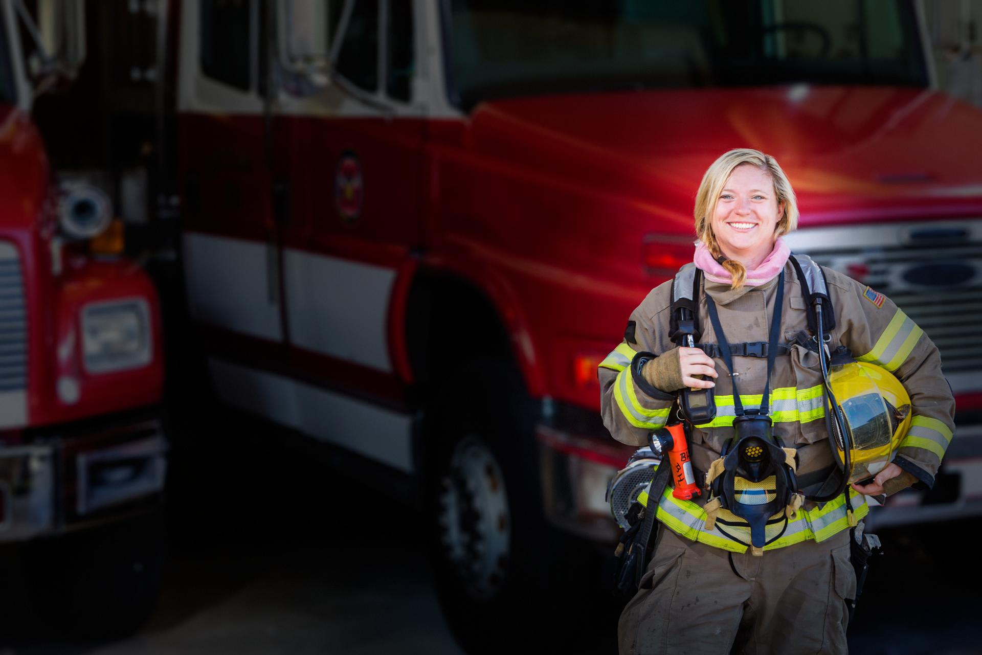 A woman firefighter standing in front of a fire truck