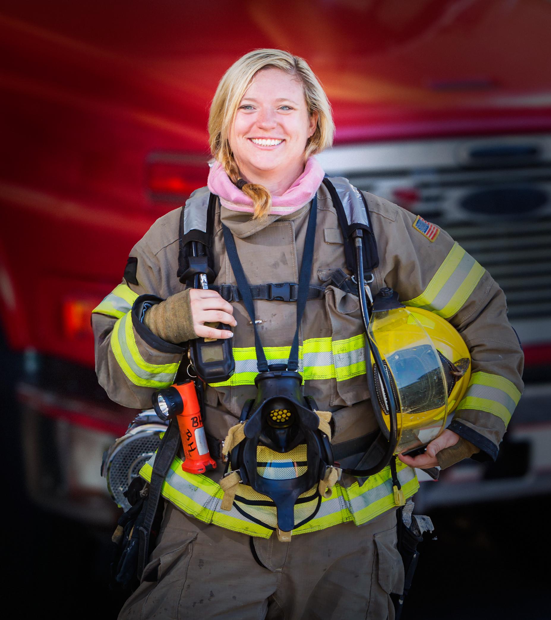 A woman firefighter standing in front of a fire truck