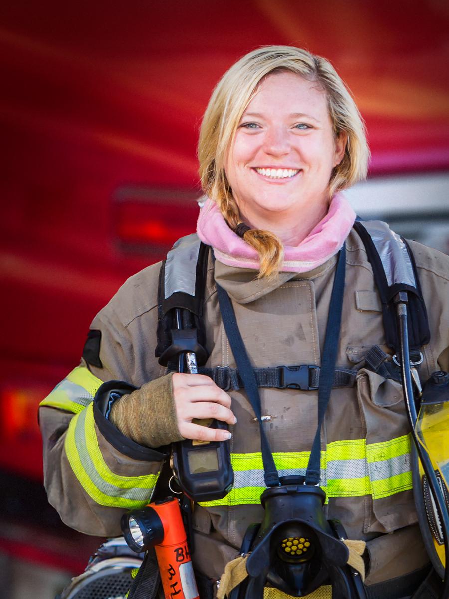 A woman firefighter standing in front of a fire truck