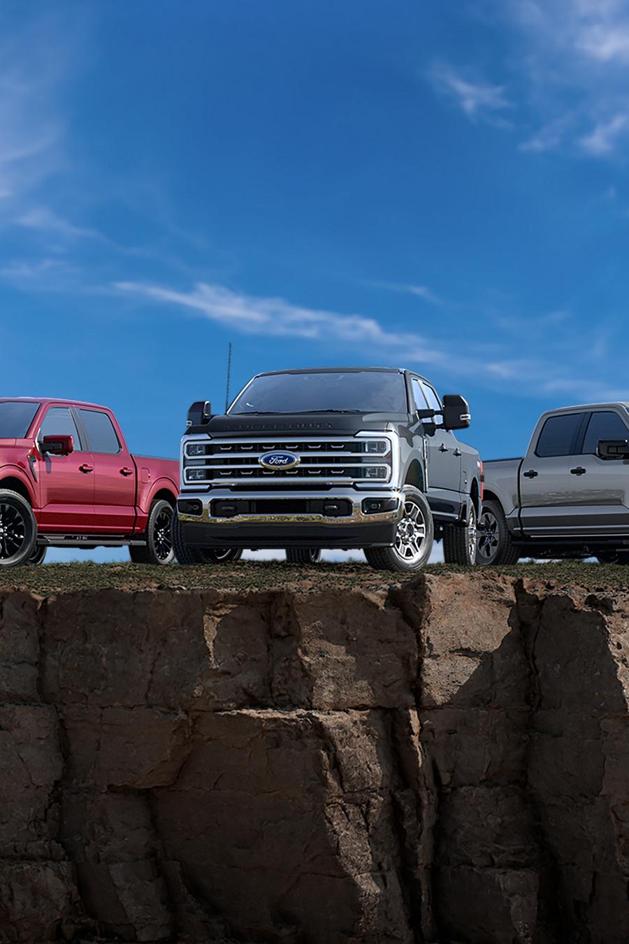 Three Ford F-150® trucks parked on the edge of cliff with a big blue sky in the background