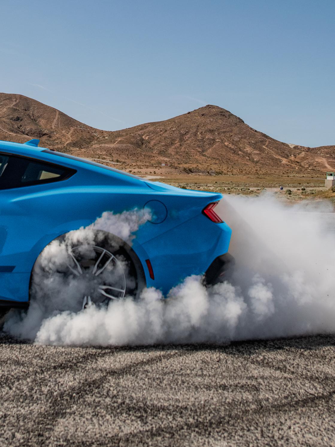 The rear tires of a Ford Mustang® coupe as the driver does a burnout in the desert