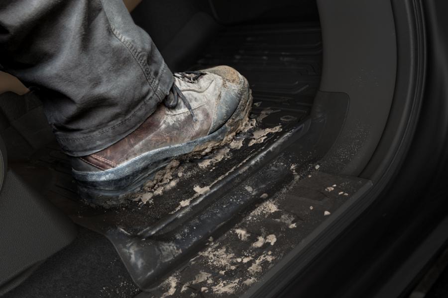 Close-up of a persons muddy boot on the rubber floor mats