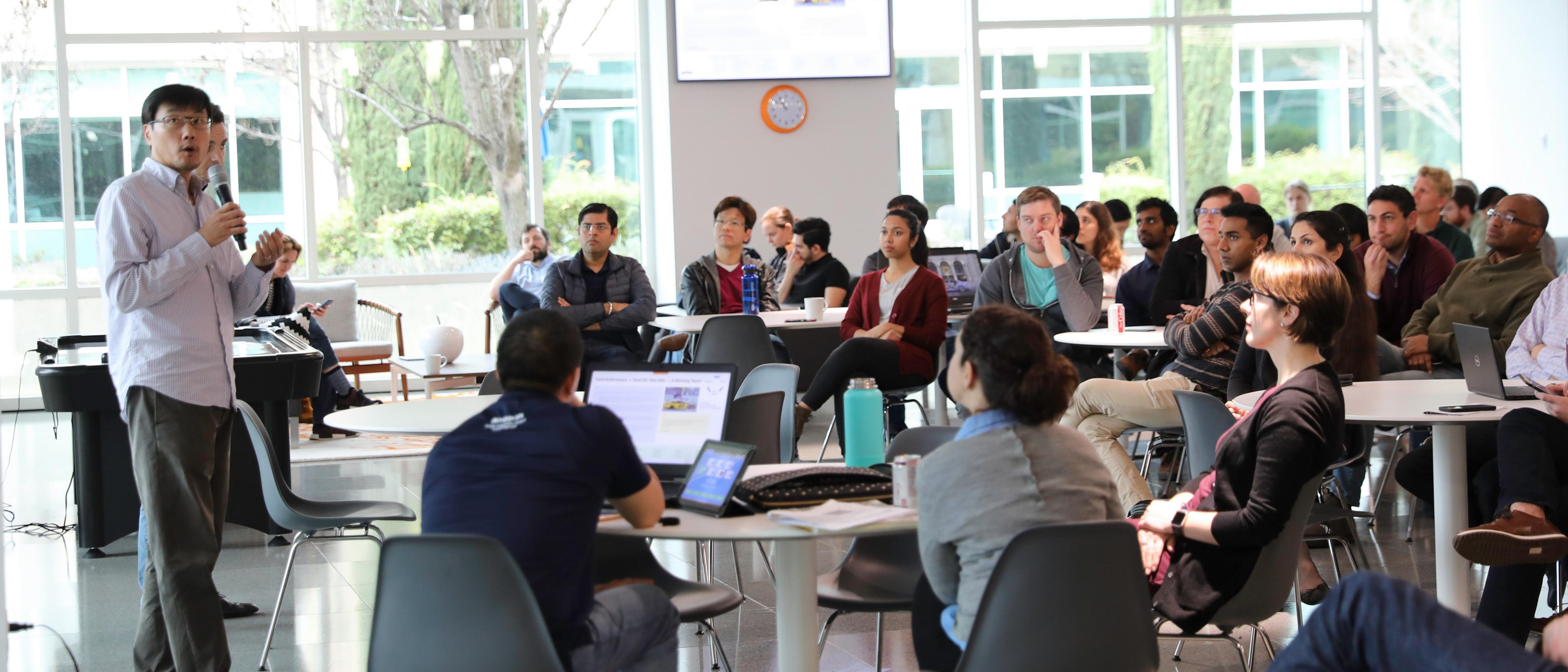 A collaborative team gathers in an open room with large windows