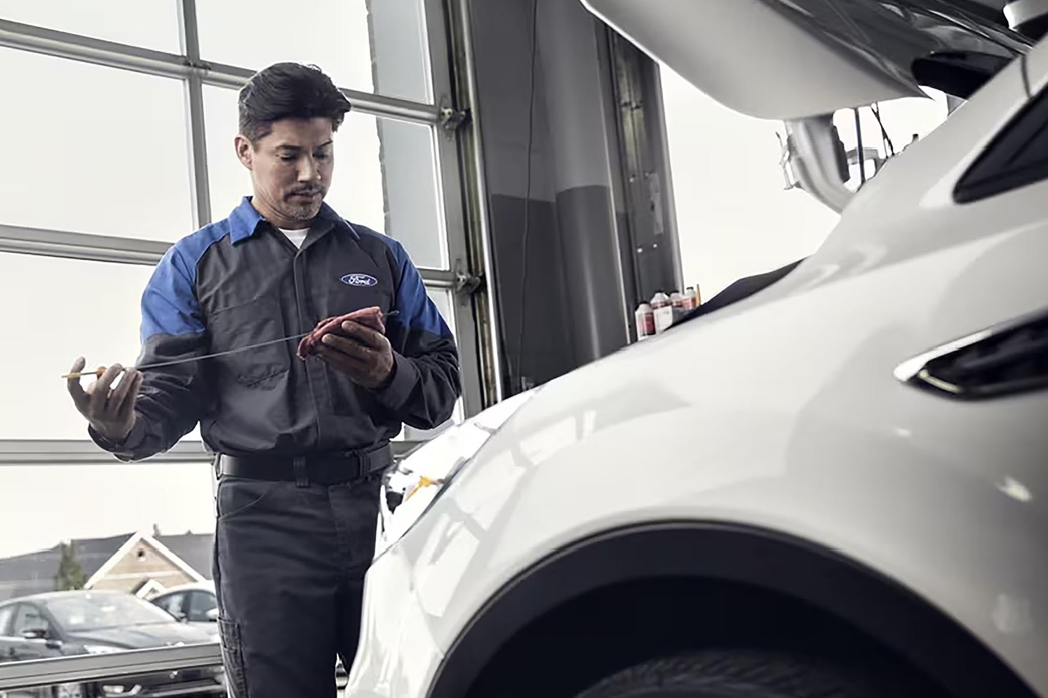 Ford factory-trained technician inspecting a vehicle under the hood
