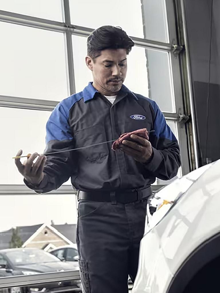 A Ford service technician checks the oil of a vehicle
